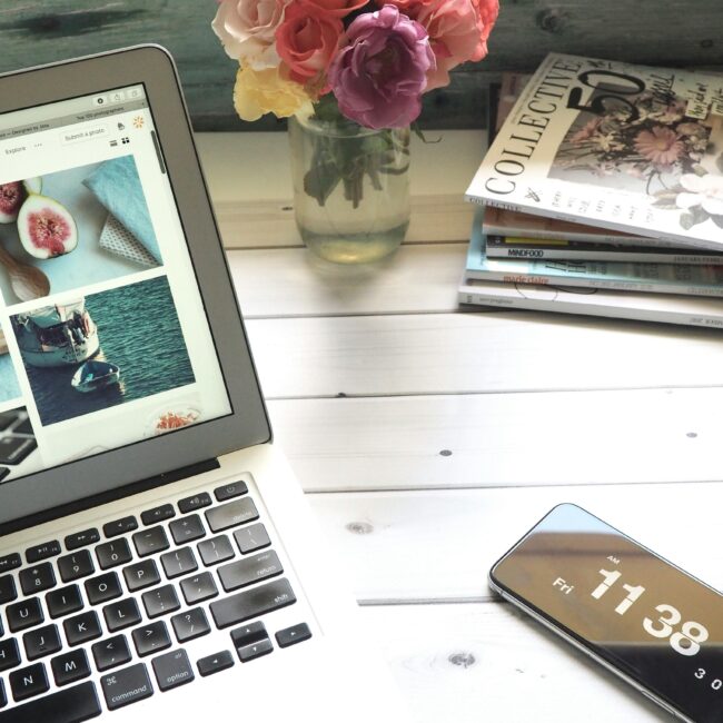 Elegant workspace featuring a laptop, smartphone, and fresh roses in a bright setting.